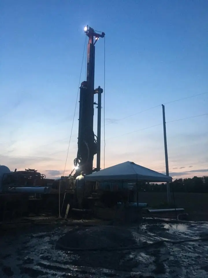 A drilling mast standing against the evening sky at the end of a shift.