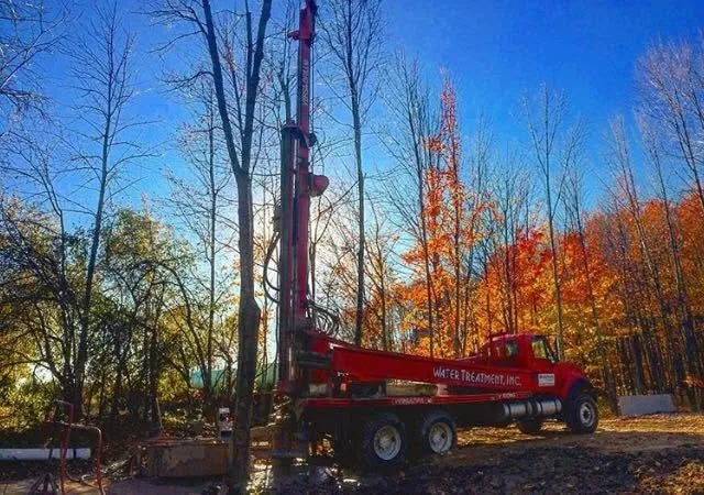 Wahlfield drill rig set up against an autumn treeline in West Michigan.