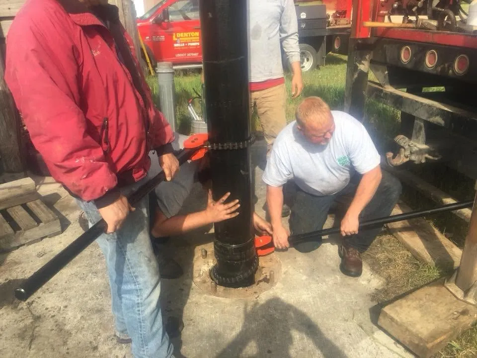 Two of the crew setting casing at the top of a new borehole.